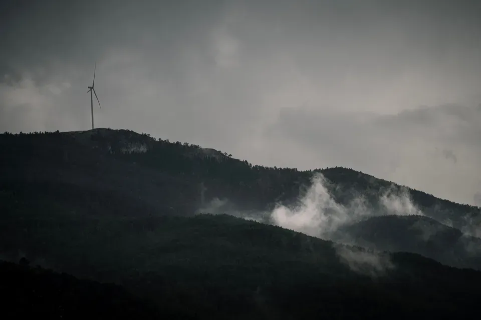 A wind turbine on a misty mountain ridge