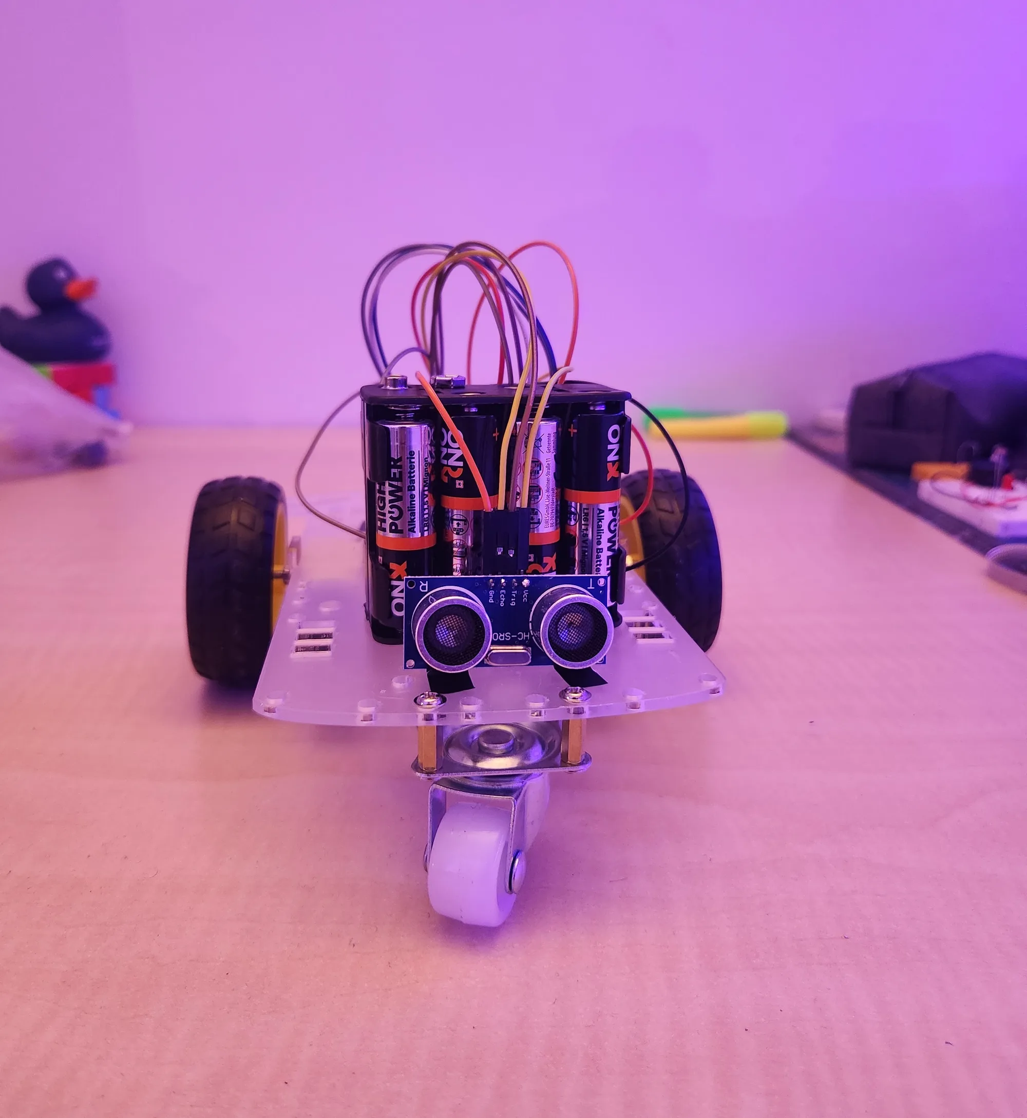 Collision avoidance robot on a clear two-wheel chassis, with an HC-SR04 ultrasonic sensor at the front