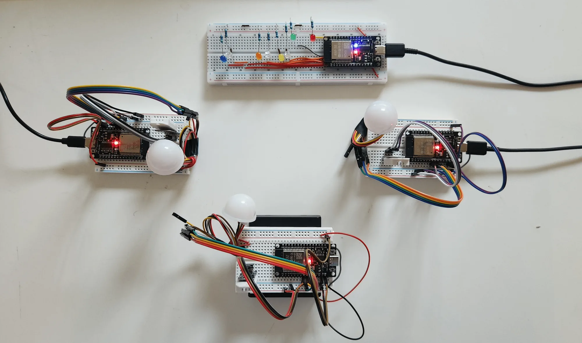 Three ESP32 sensor nodes on breadboards around the gateway board and its row of status LEDs